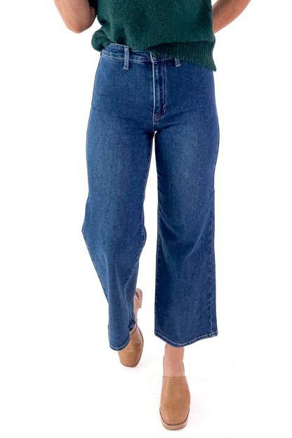 Front view of woman wearing green sweater with Dark Wash No Pocket Trouser Jeans against white studio background.