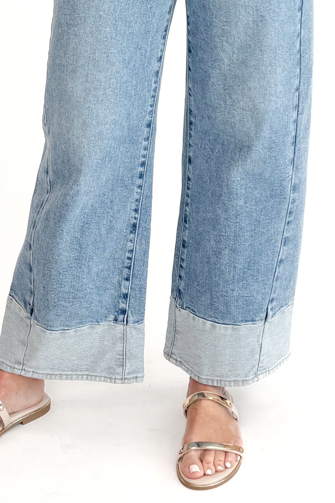 Front detail view of woman wearing Light Wash Two Toned Jeans by Just Black Denim with white sweater against white studio background.