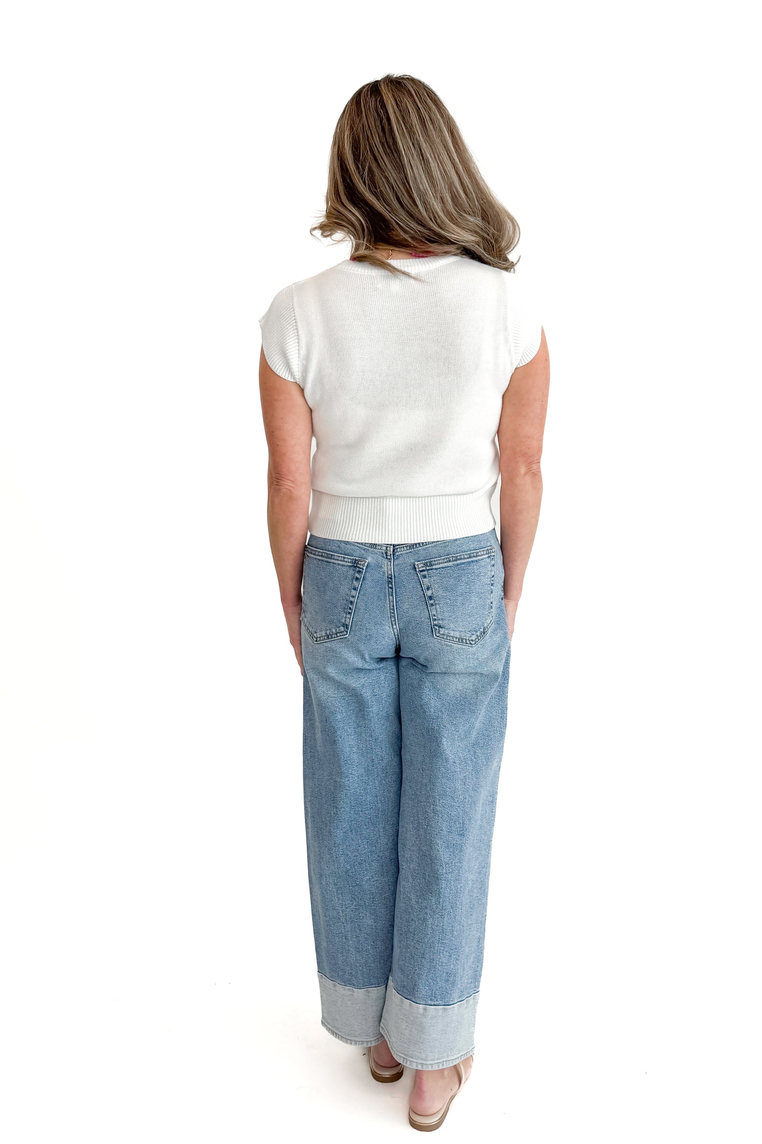 Back view of woman wearing Light Wash Two Toned Jeans by Just Black Denim with white sweater against white studio background.