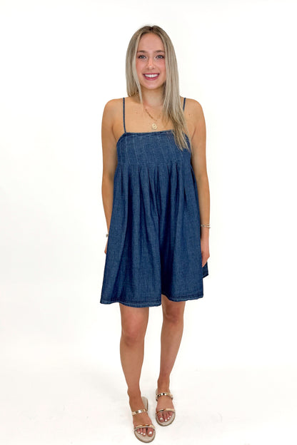 Front view of woman wearing Denim Pleat Detail Tank Dress with sandals against white studio background.