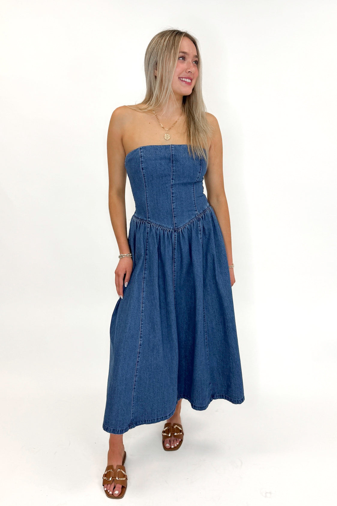 Front view of woman wearing Denim V-Waist Midi Dress with sandals against white studio background.