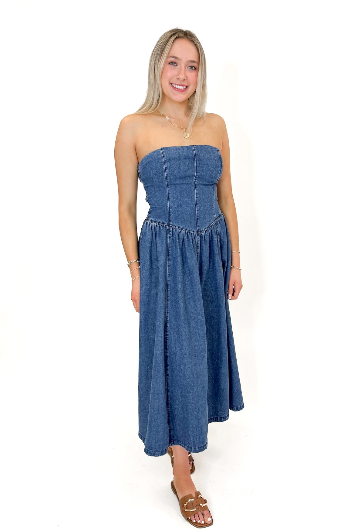 Side view of woman wearing Denim V-Waist Midi Dress with sandals against white studio background.