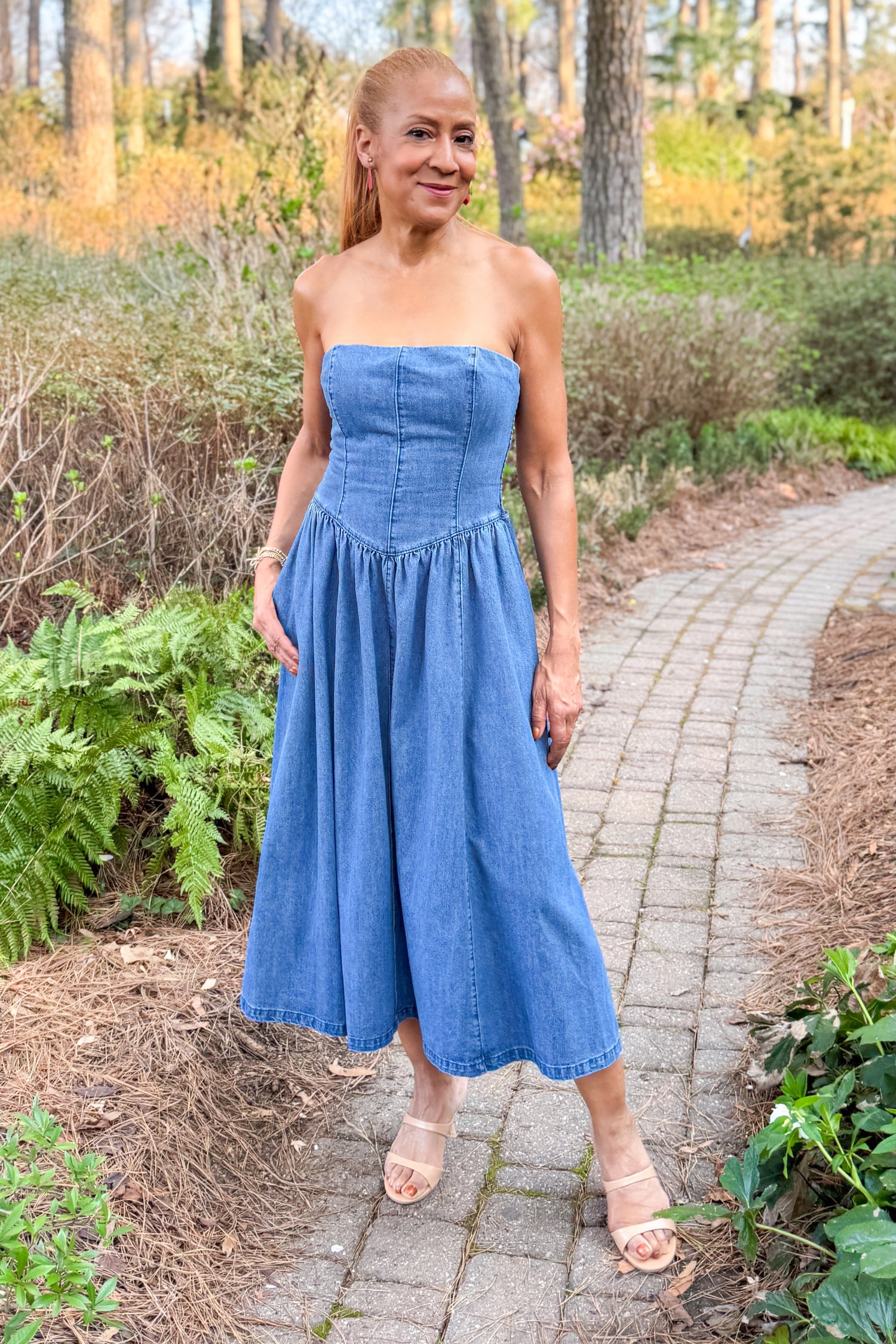 Front view of woman wearing Denim V-Waist Midi Dress with heels outside at a garden.