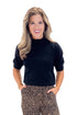 Front view of woman wearing Black Puff Short Sleeve Sweater with Leopard Pants against white studio background.