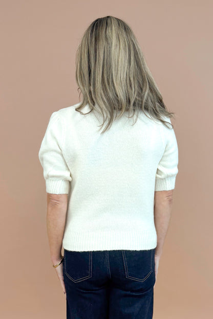 Back view of woman wearing Cream Puff Short Sleeve Sweater and blue jeans. 