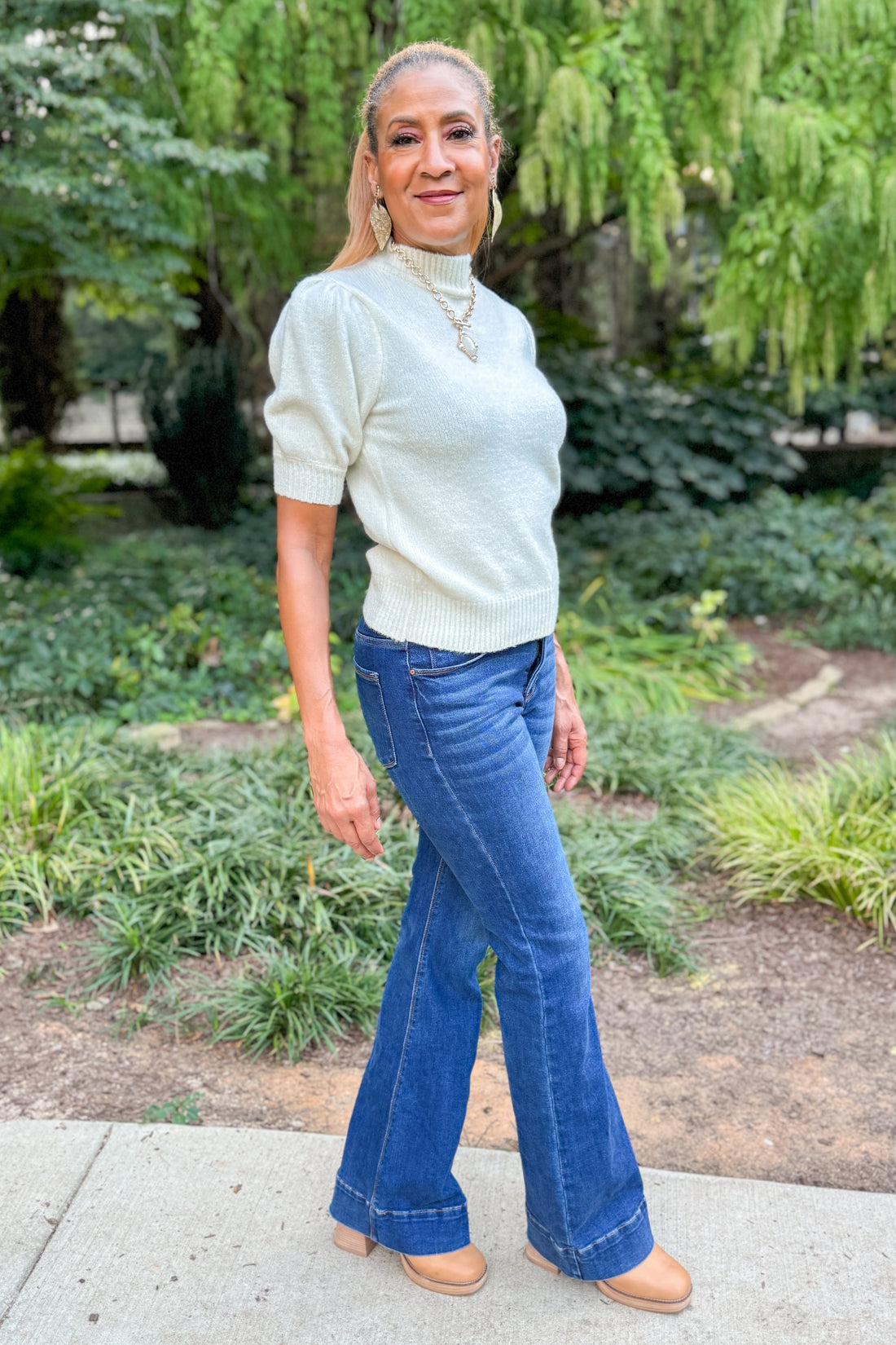 Side view of woman wearing Cream Puff Short Sleeve Sweater and blue jeans outside walking.