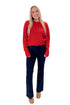 Front view of woman wearing Red Ribbed Neck Sweater with jeans against white studio background.
