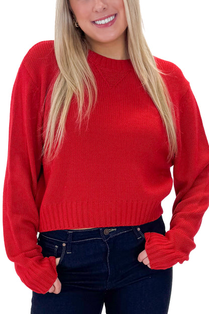 Front detail view of woman wearing Red Ribbed Neck Sweater with jeans against white studio background.