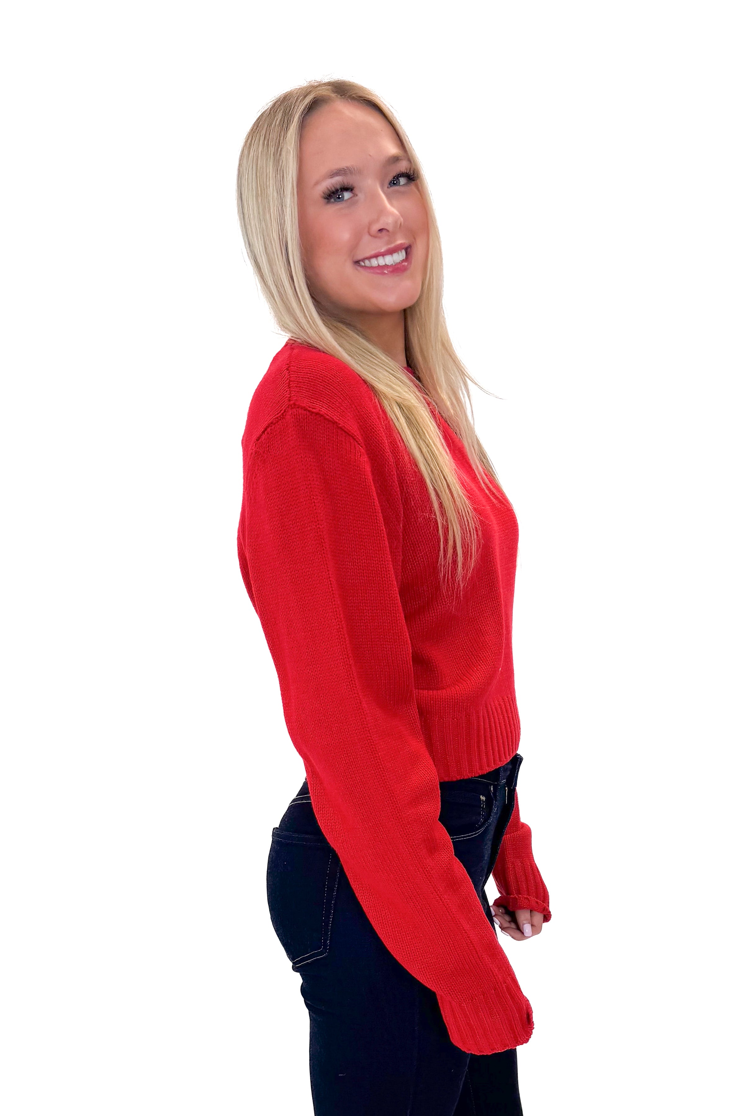Side view of woman wearing Red Ribbed Neck Sweater with jeans against white studio background.
