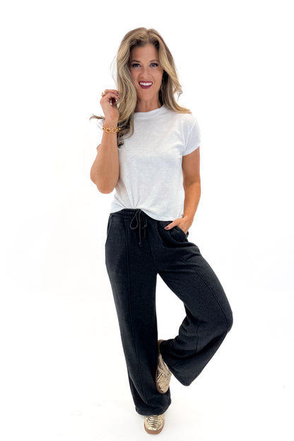 Front view of woman wearing Washed Black Drawstring Sweatpants with white top against white studio background.