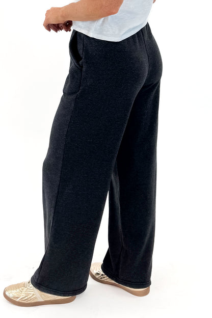 Side view of woman wearing Washed Black Drawstring Sweatpants with white top against white studio background.