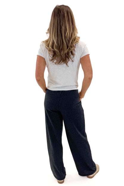 Back view of woman wearing Washed Black Drawstring Sweatpants with white top against white studio background.