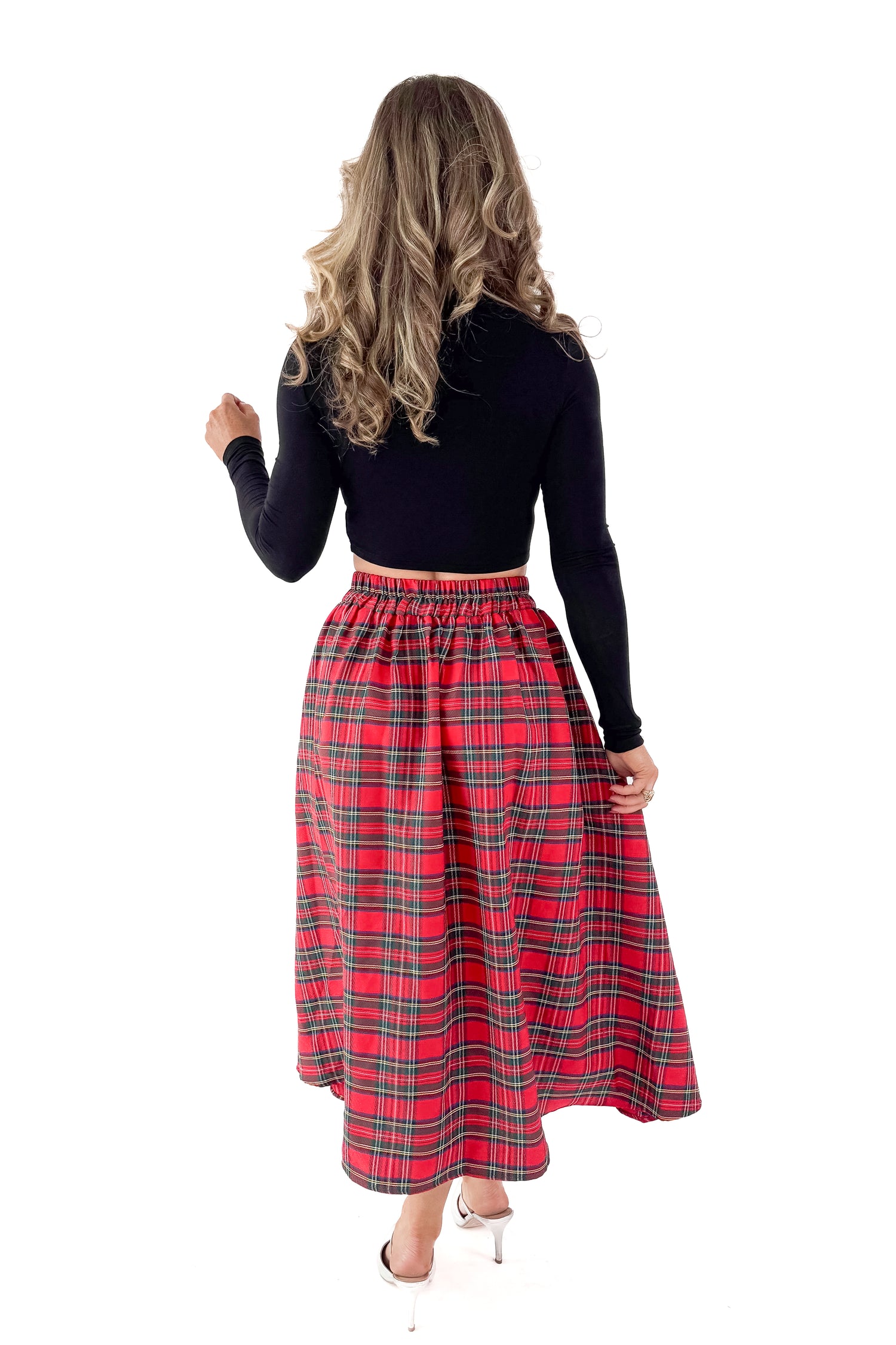 Back view of woman wearing black top with skirt against white studio background.