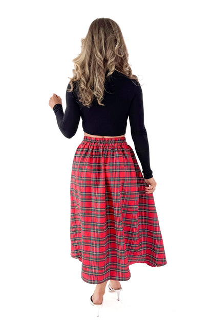Back view of woman wearing black top with skirt against white studio background.
