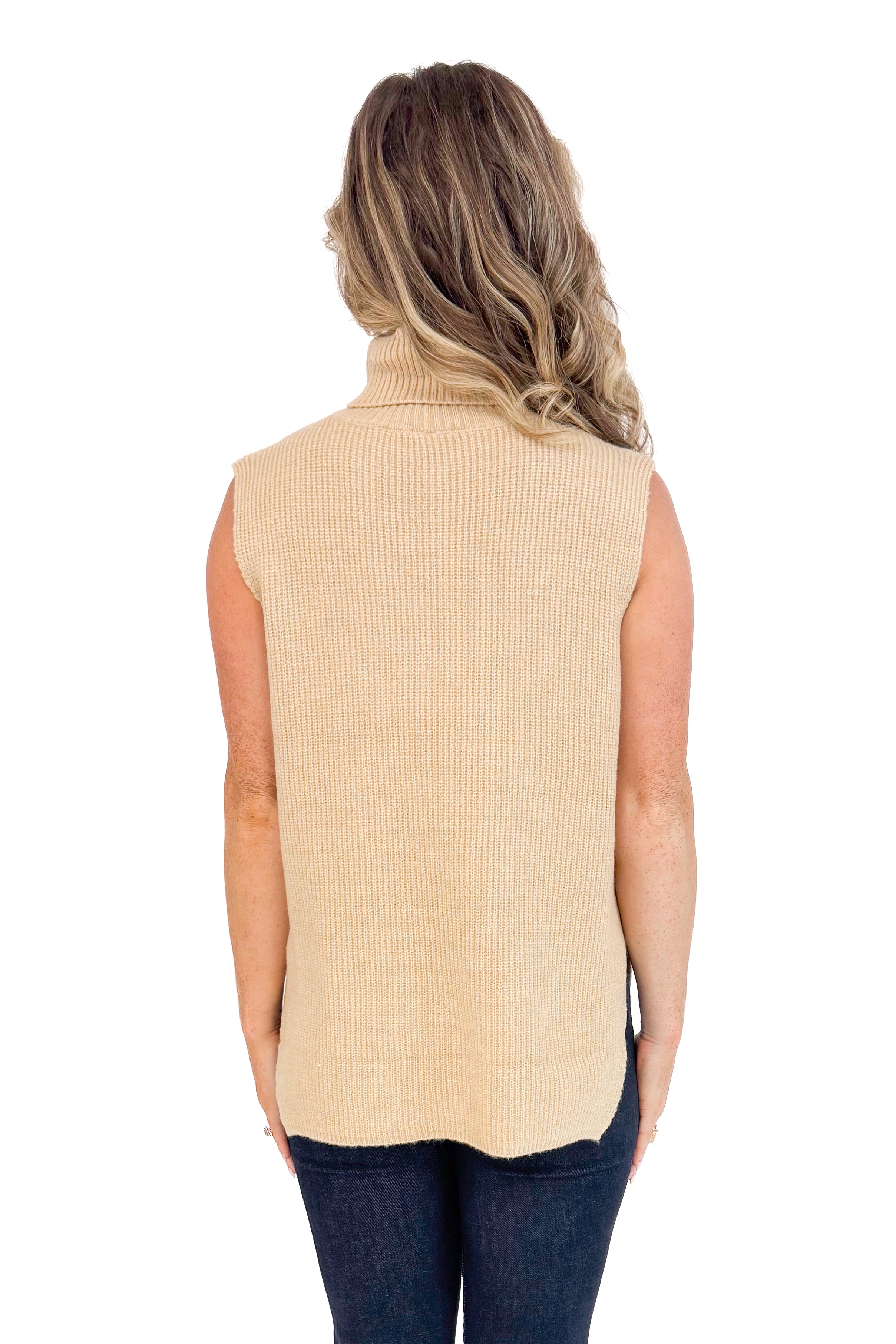 Back studio picture of woman wearing Taupe Turtleneck Sweater Vest and jeans with a white background.