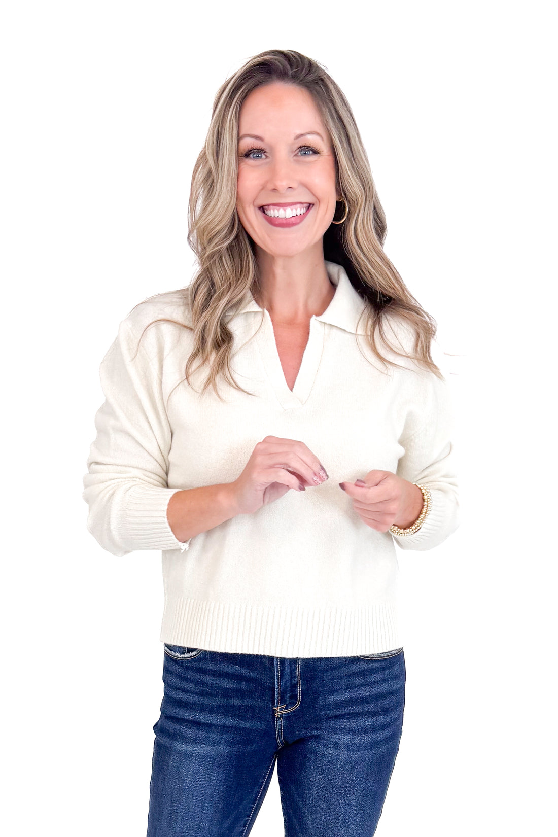 Woman wearing a white sweater and blue jeans on a white background