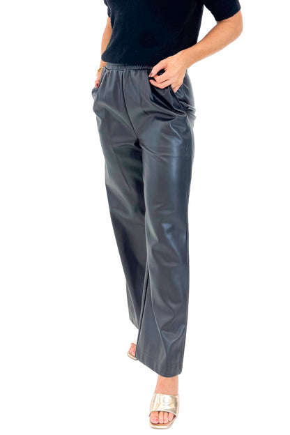 Front detail view of woman wearing Black Faux Leather Pants with black sweater against white studio background.