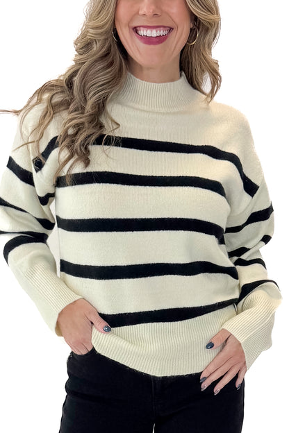 Front view of woman wearing Black &amp; Cream Striped Mock Neck Sweater with jeans against white studio background.