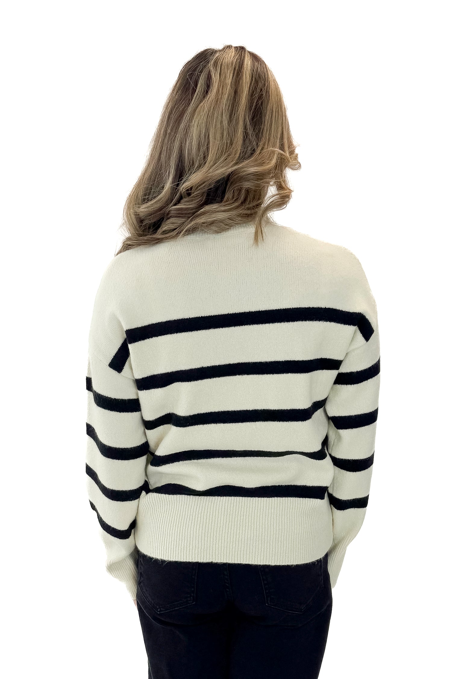 Back view of woman wearing Black &amp; Cream Striped Mock Neck Sweater with jeans against white studio background.