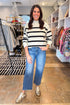 Front view of woman wearing Black & Cream Striped Mock Neck Sweater with jeans at a boutique.