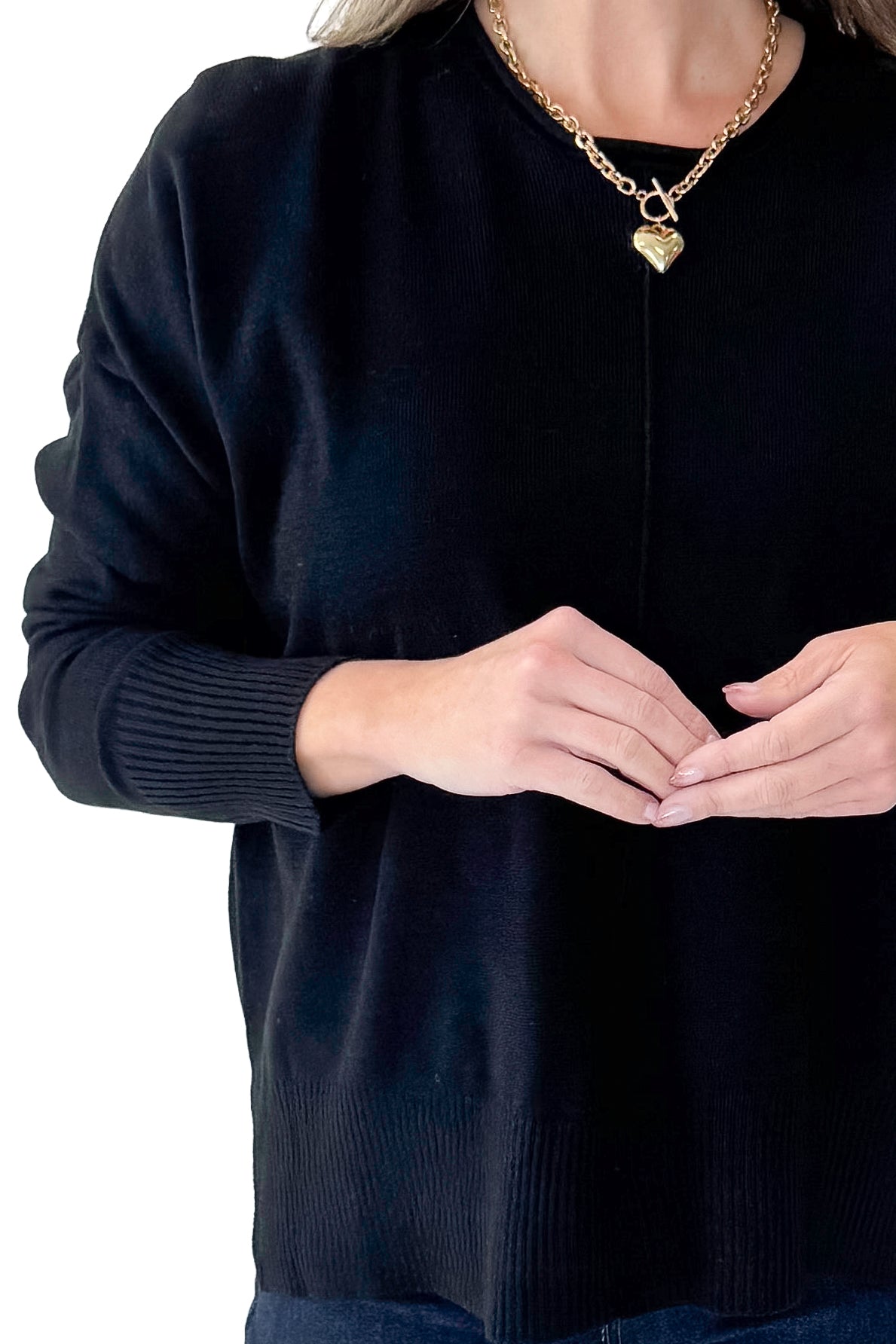 Front detailed view of woman wearing Black Center Seam Round Neck Sweater with jeans against white studio background.