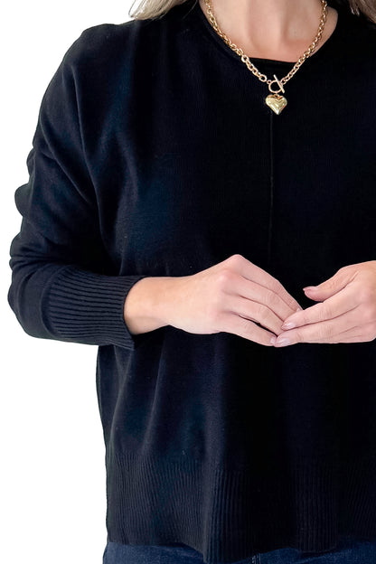 Front detailed view of woman wearing Black Center Seam Round Neck Sweater with jeans against white studio background.