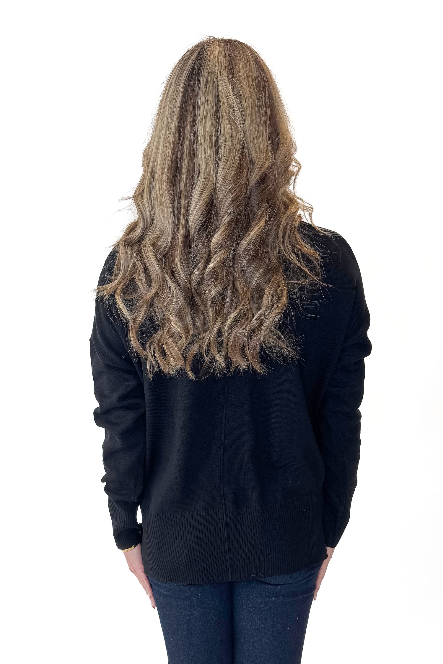 Back view of woman wearing Black Center Seam Round Neck Sweater with jeans against white studio background.