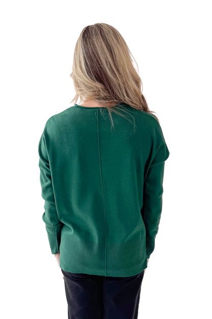 Back view of woman wearing Green Center Seam Round Neck Sweater with jeans against white studio background.
