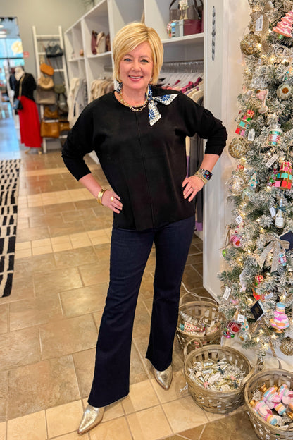 Front view of woman wearing Black Center Seam Round Neck Sweater with jeans at a boutique.