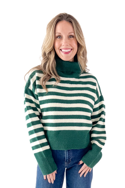 Front view of woman wearing Green &amp; Cream Striped Turtleneck Sweater with jeans against white studio background.