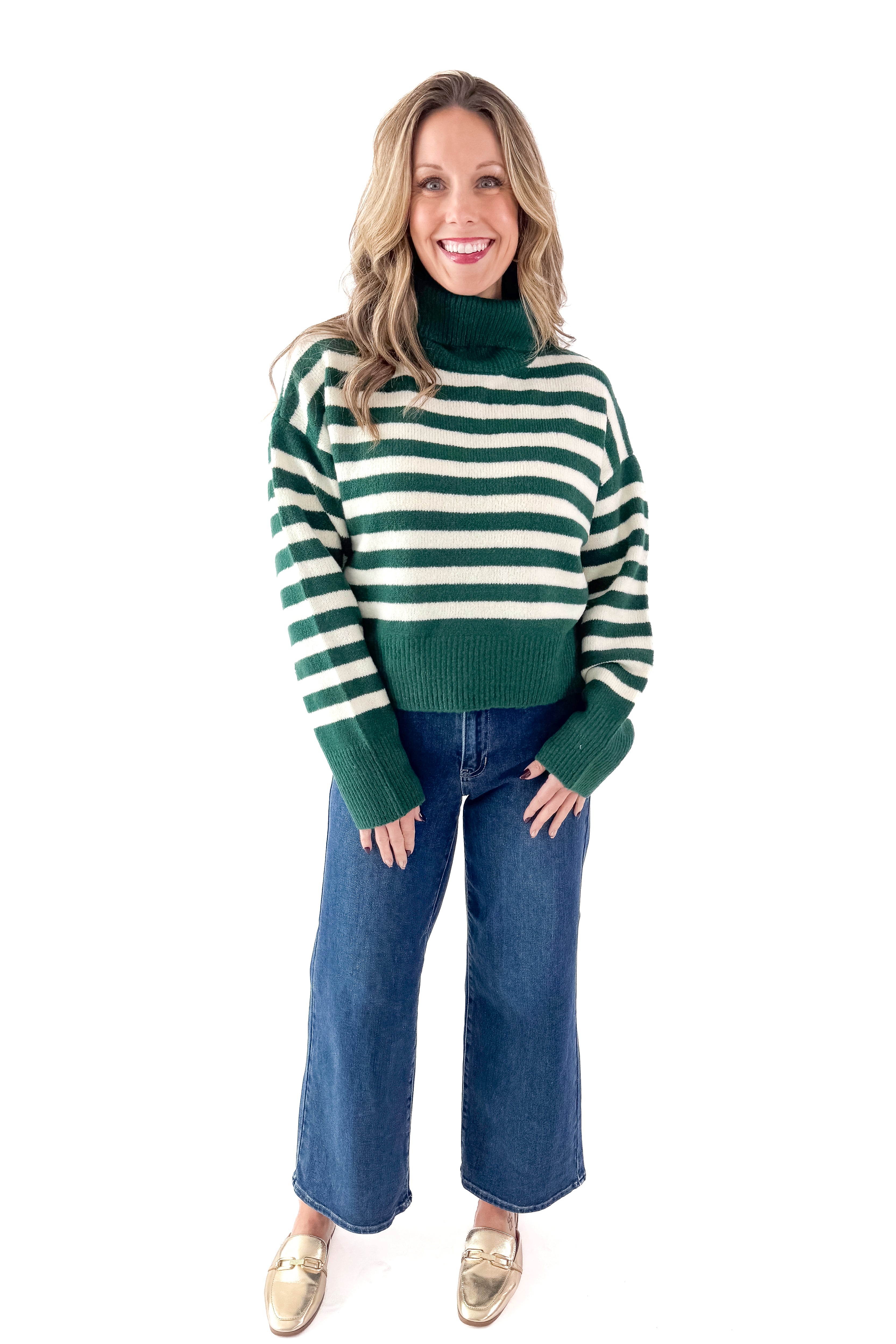 Front view of woman wearing Green &amp; Cream Striped Turtleneck Sweater with jeans against white studio background.