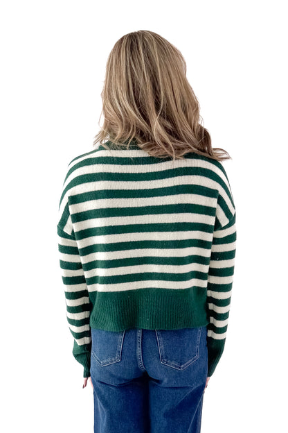 Back view of woman wearing Green &amp; Cream Striped Turtleneck Sweater with jeans against white studio background.