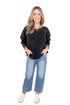 Front view of woman wearing washed black waffle top with jeans against white studio background.