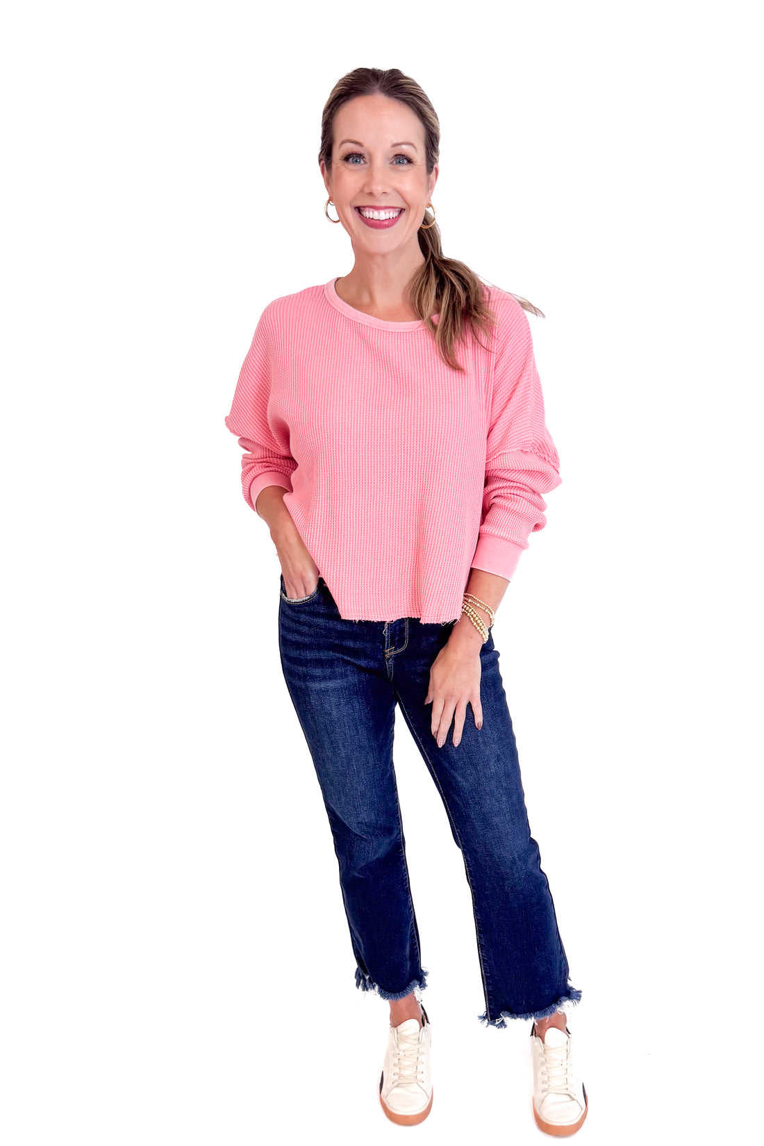 Woman wearing a pink sweater and blue jeans on a white background