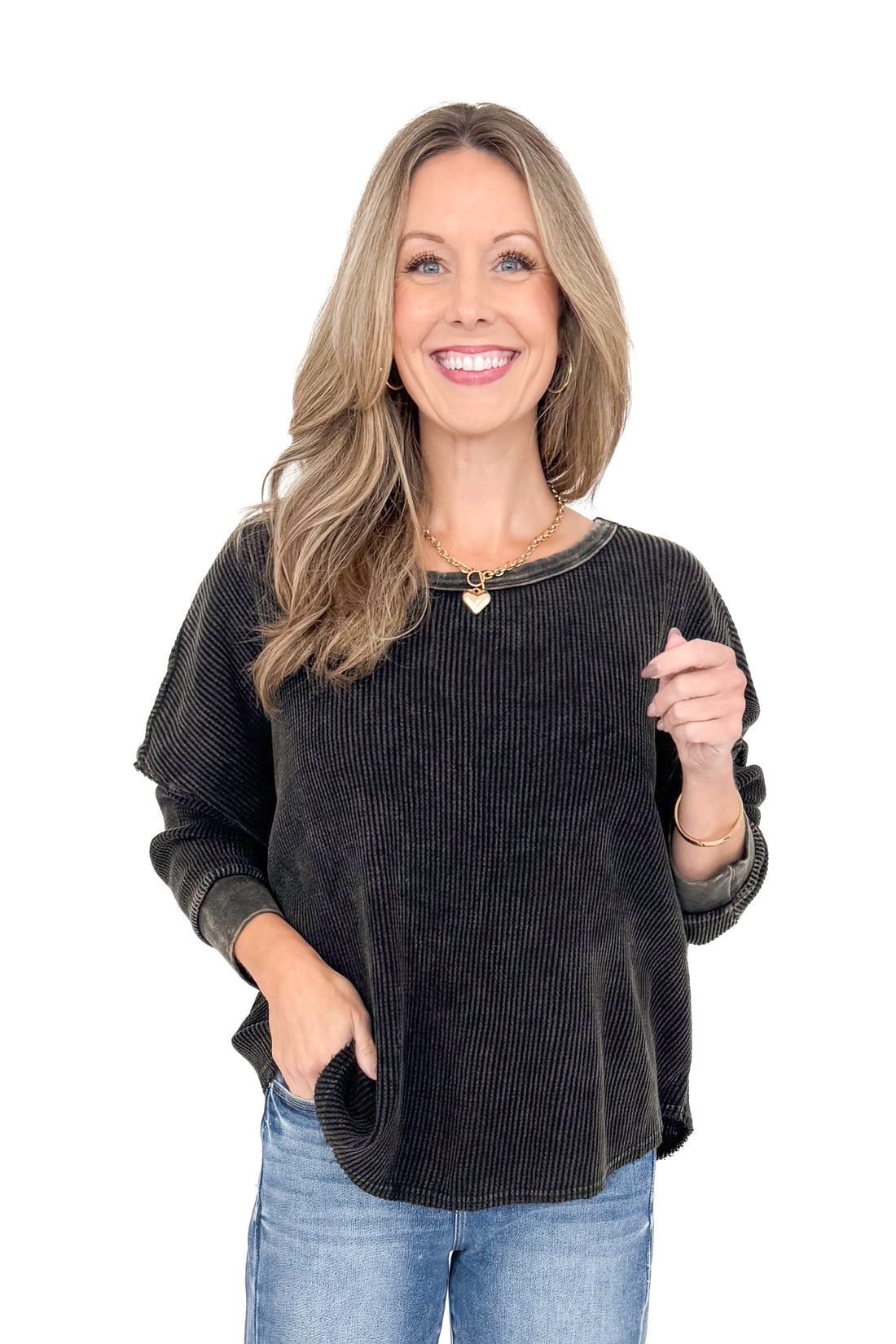 Front view of woman wearing washed black waffle top with jeans against white studio background.