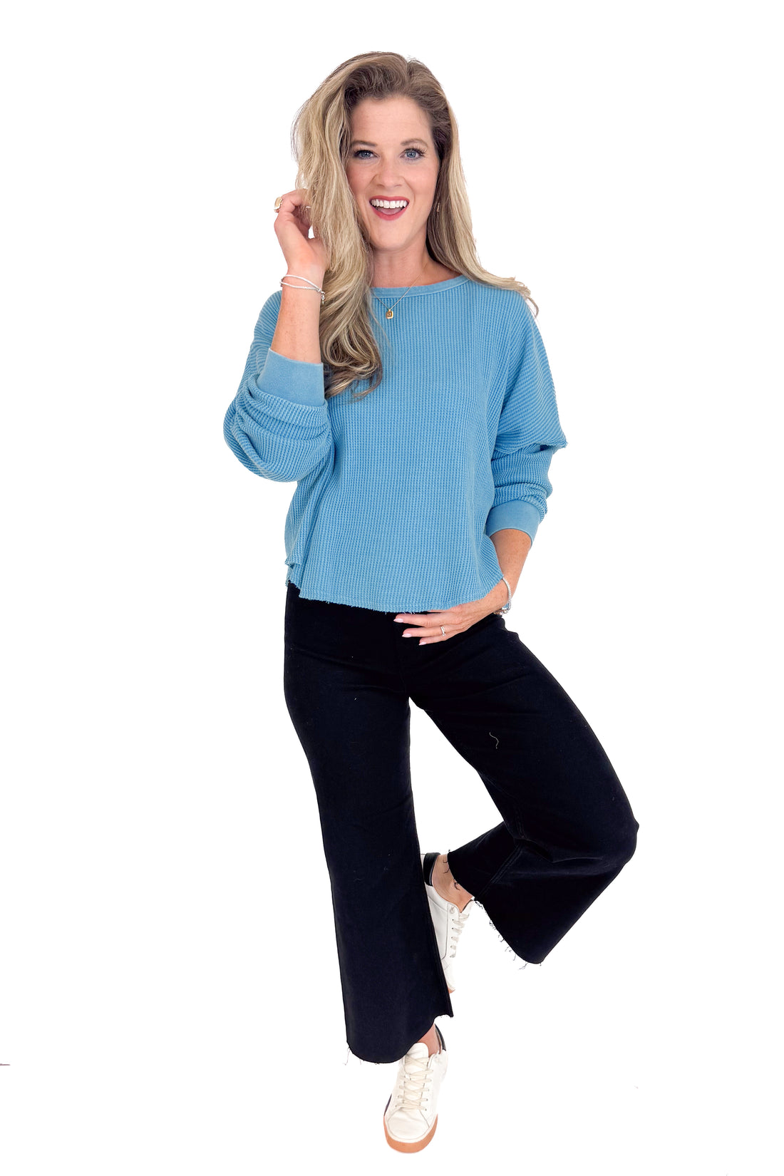 Woman wearing a blue top and black pants on a white background