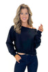 Front view of woman wearing Black Boatneck Banded Sweatshirt with jeans against white studio background.