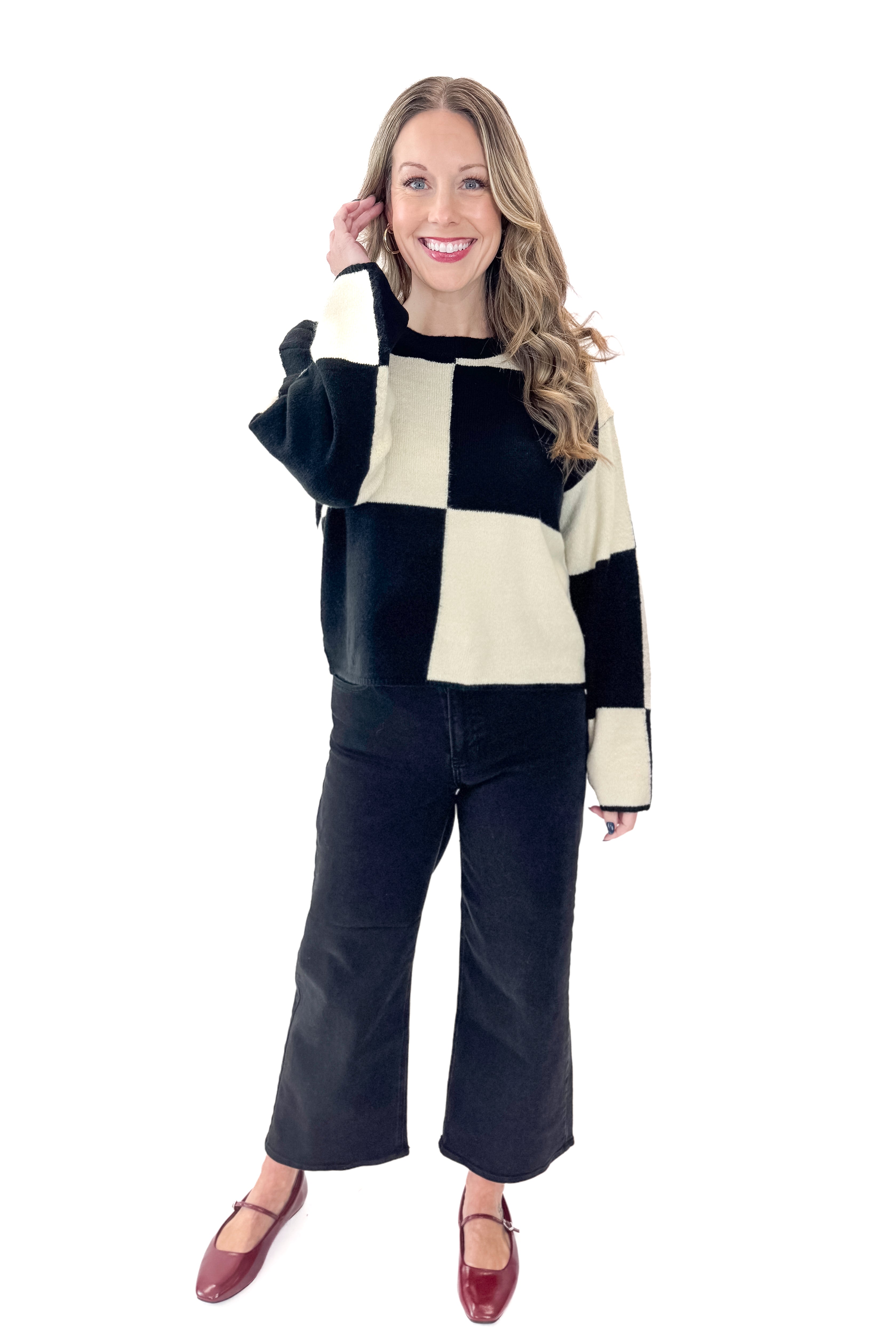 Front view of woman wearing Black &amp; Cream Checkered Sweater with jeans against white studio background.