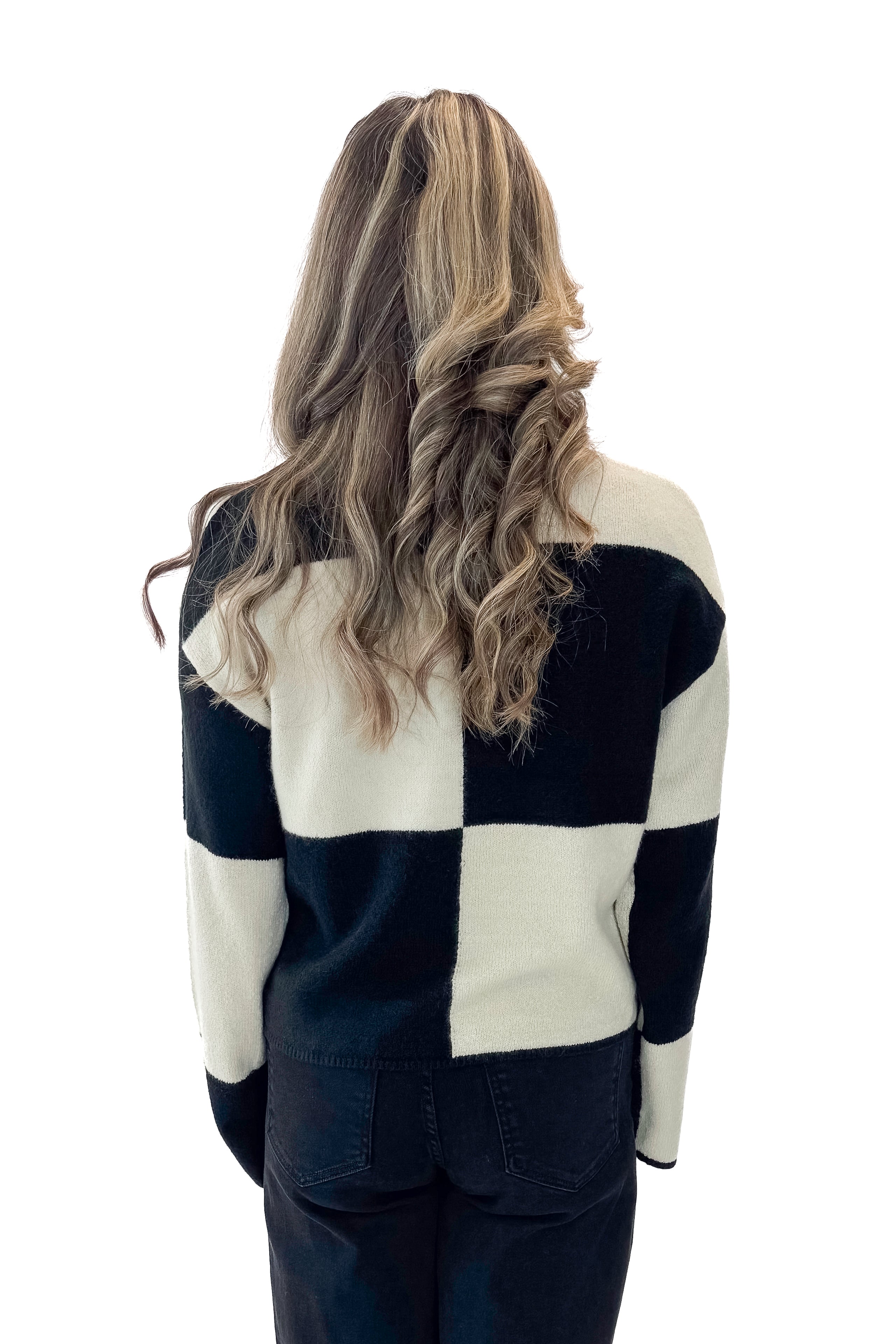Back view of woman wearing Black &amp; Cream Checkered Sweater with jeans against white studio background.