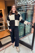 Front view of woman wearing Black & Cream Checkered Sweater with jeans at a boutique.