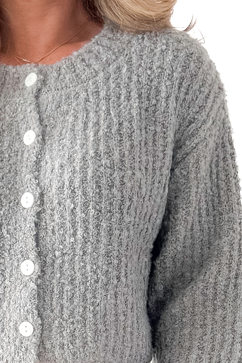 Front detail view of woman wearing Grey Ribbed Button Up Cardigan against white studio background.