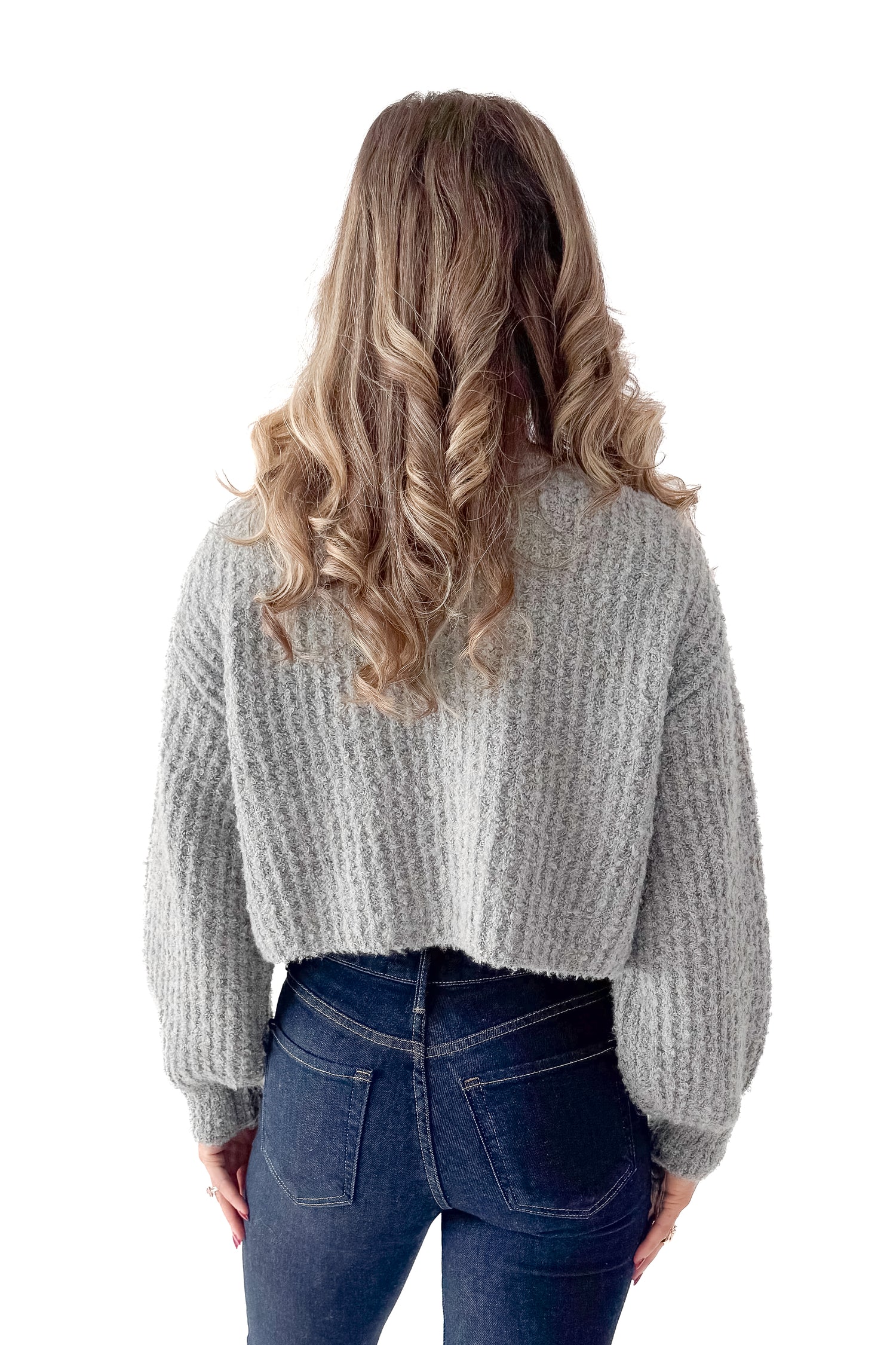 Back view of woman wearing Grey Ribbed Button Up Cardigan with jeans against white studio background.