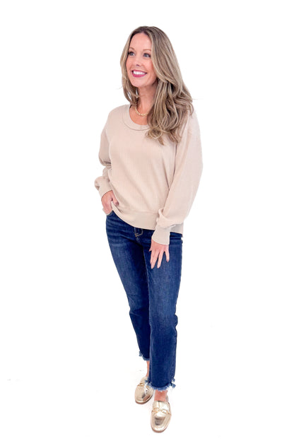 Front view of woman wearing Washed Taupe Round Neck Waffle Weave Top and blue jeans against a white background.
