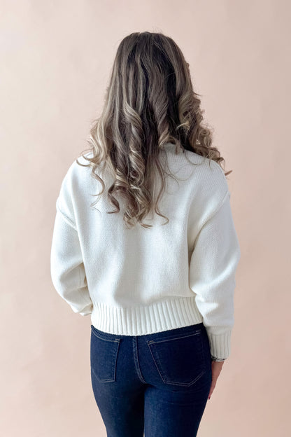 Back view of woman wearing Cream Seam Split Detail Sweater with jeans against tan studio background.