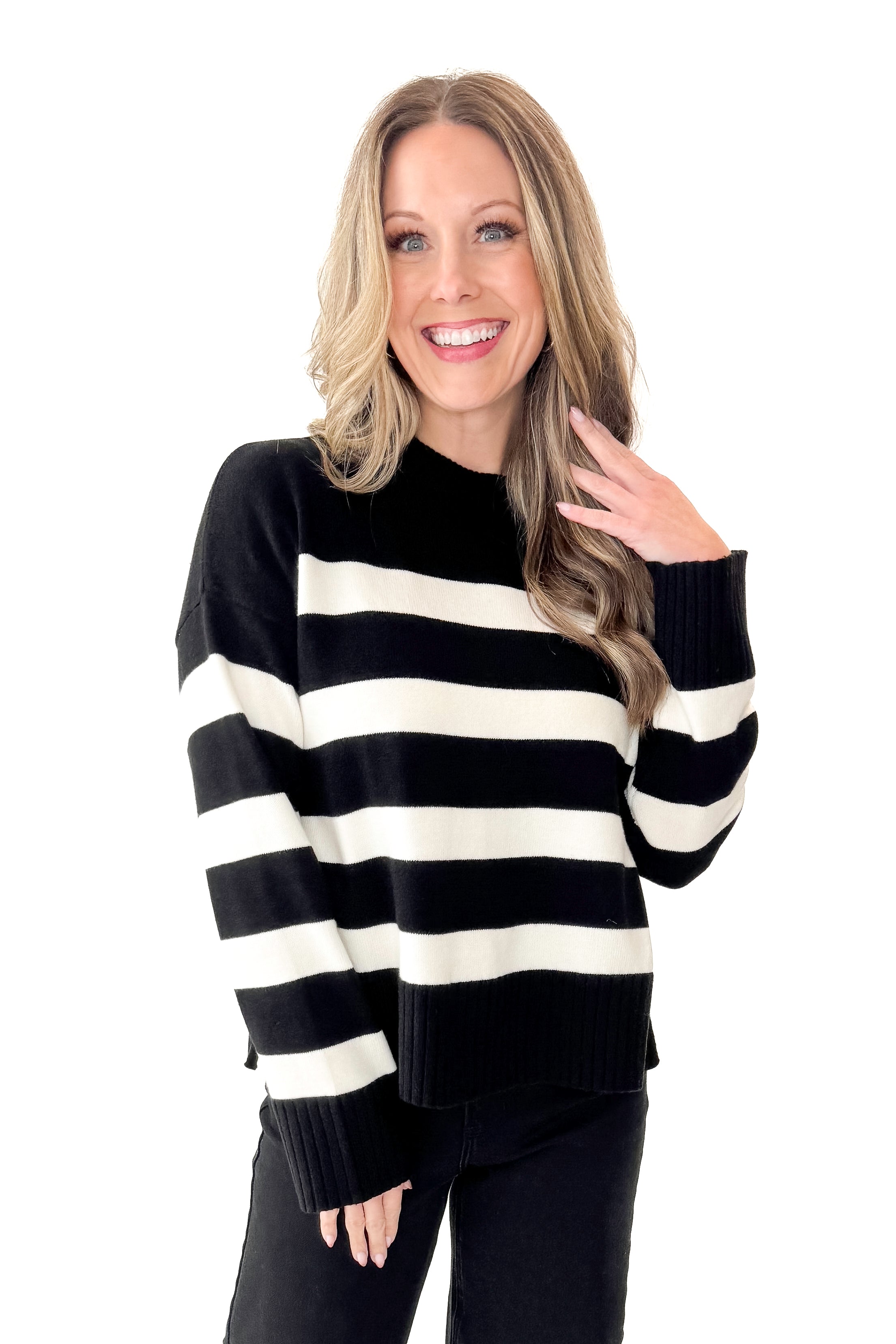 Front view of woman wearing Black and Cream Striped Crewneck Sweater with jeans against white studio background.