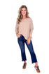 Woman wearing a beige striped sweater and blue jeans on a white background