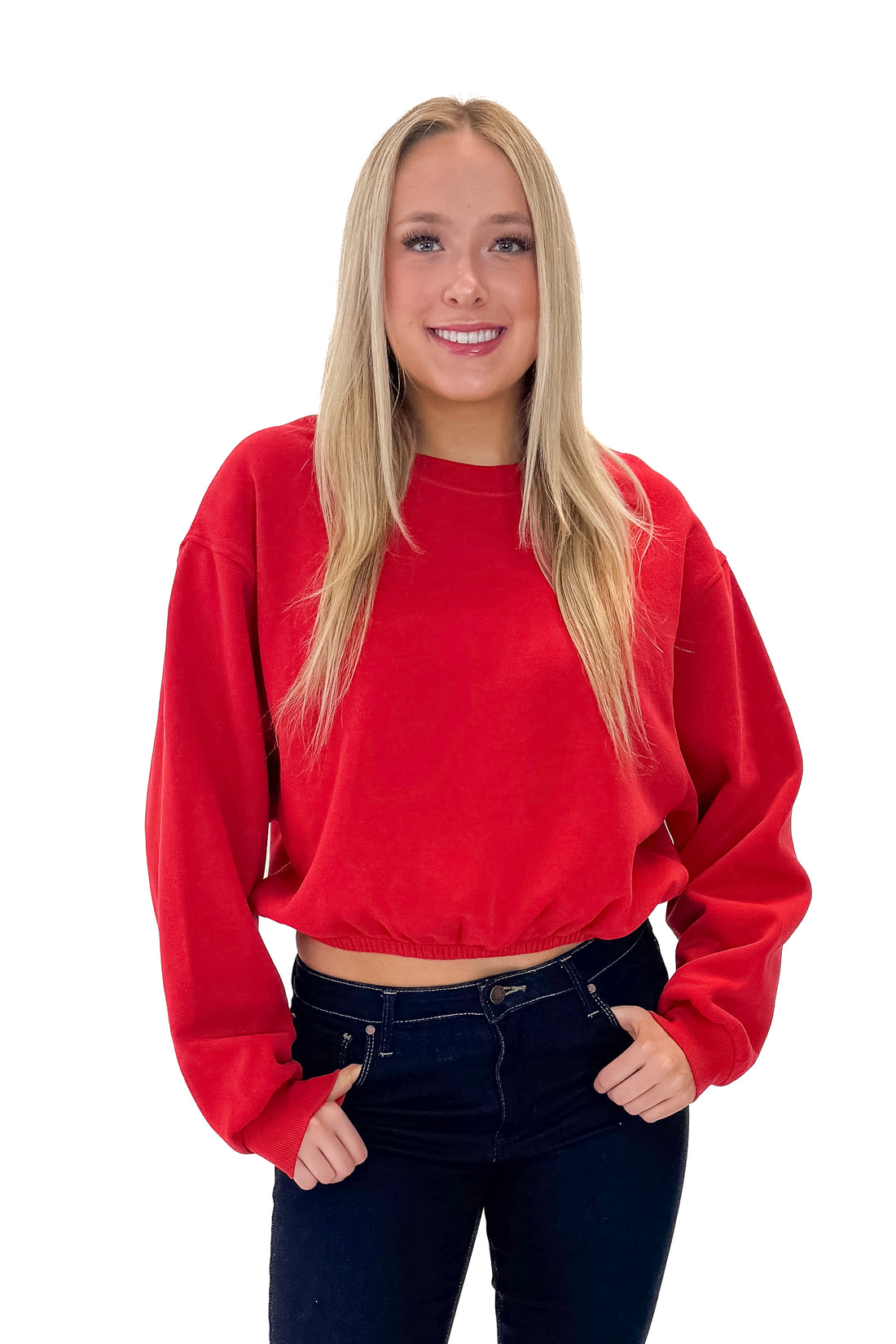 Front view of woman wearing Red Elastic Hem Sweatshirt with jeans against white studio background.