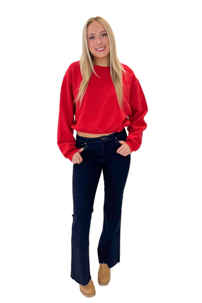 Front view of woman wearing Red Elastic Hem Sweatshirt with jeans against white studio background.