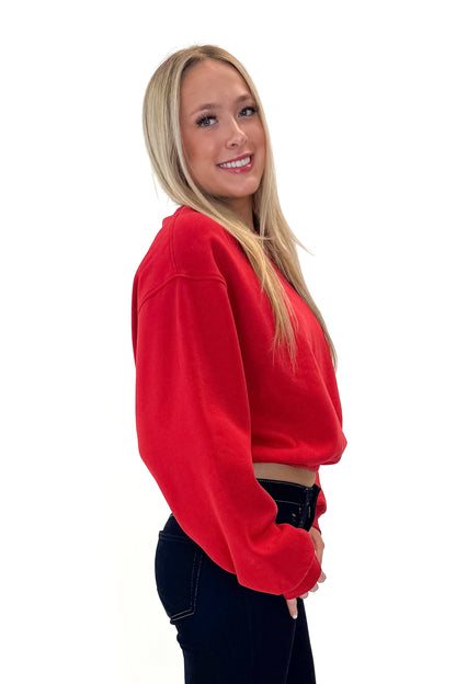 Side view of woman wearing Red Elastic Hem Sweatshirt with jeans against white studio background.