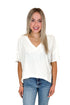 Front view of woman wearing Cream V-Neck Tee with jeans against white studio background